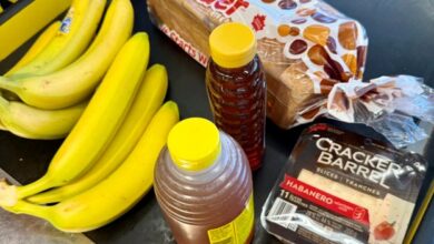 Bananas, two yellow-capped honey bottles, a loaf of Wonder bread, and Cracker Barrel habanero cheese slices on a checkout belt.