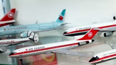 Several Air Canada toy model airplanes arranged on a glass shelf, red and white liveries with maple leaf logos.