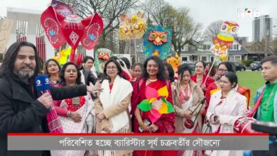 News reporter in a dark coat with a blue mic interviewing a group of women in red and white traditional clothing, holding colorful lanterns and festival props outdoors in a park.