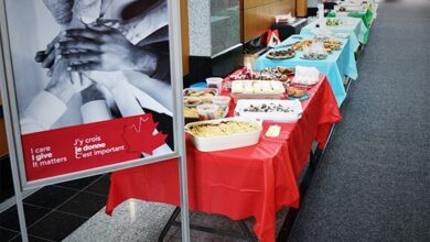 Buffet tables with colorful cloths and dishes lined up in a hallway at a conference or event, with a poster on the left.