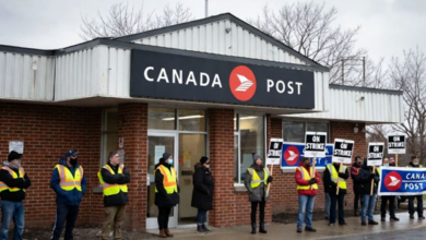 Line of people in high-visibility vests holding 'ON STRIKE' signs outside a Canada Post building.
