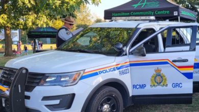 RCMP police vehicle with a push bumper at an outdoor community event; a Hamilton Community Centre tent is in the background.