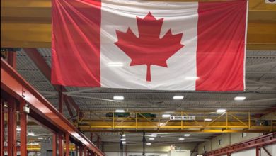 Canadian flag hanging inside a large industrial workshop with overhead crane and machinery