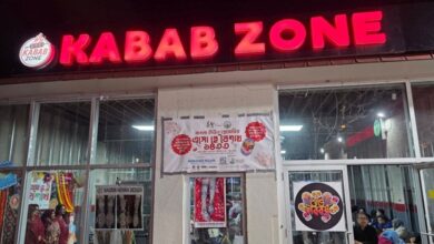Front of a kebab shop with a bright red 'KABAB ZONE' sign and glass doors showing customers inside, at night.