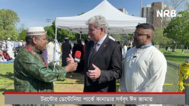 Reporter from NRB HD interviews a suited man and a man in white traditional attire at an Eid gathering in a park with a white canopy tent nearby.