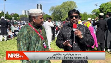 Reporter with a red NRB TV microphone interviews a man in a green traditional outfit at an outdoor crowd; NRB TV banner visible in the scene.