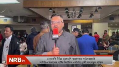News reporter with a red NRB TV microphone reporting live in a crowded indoor venue, with a caption bar at the bottom.