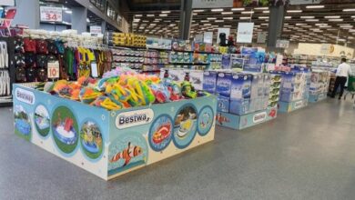 In a store, a large blue Bestway display of inflatable pool toys and other water toys in front of stacked shelves.