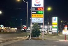Tall illuminated Pioneer gas station sign at night showing fuel prices and banners for Hasty Market and U-Haul.