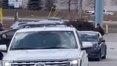 White Ford SUV in the foreground in a parking lot, with other cars and a storefront in the background.