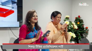 Two women in colorful sarees speak at a press conference; one holds a microphone, NRB HD logo in corner, flowers in background