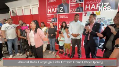 Crowd at the Ahshanul Hafiz campaign grand opening; a woman with a pink megaphone speaks to supporters, red Hafiz posters on the wall behind.