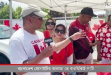Man wearing a light cap speaks into a red NRB microphone under a white canopy while others in red stand nearby, Canada flags in the background.